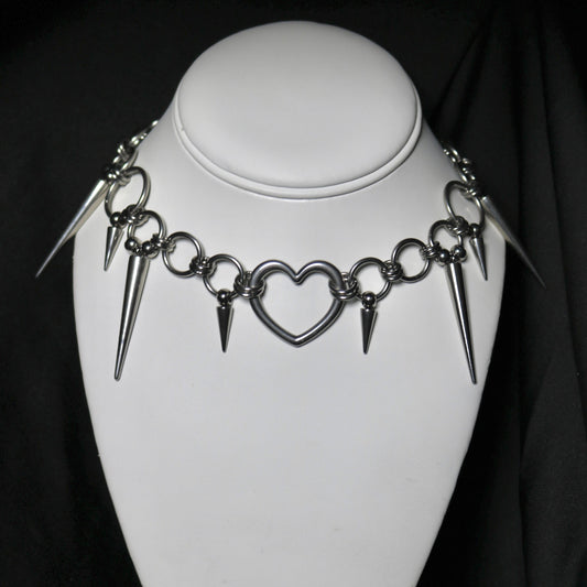 Necklace with heart and spike designs on a mannequin against a black background