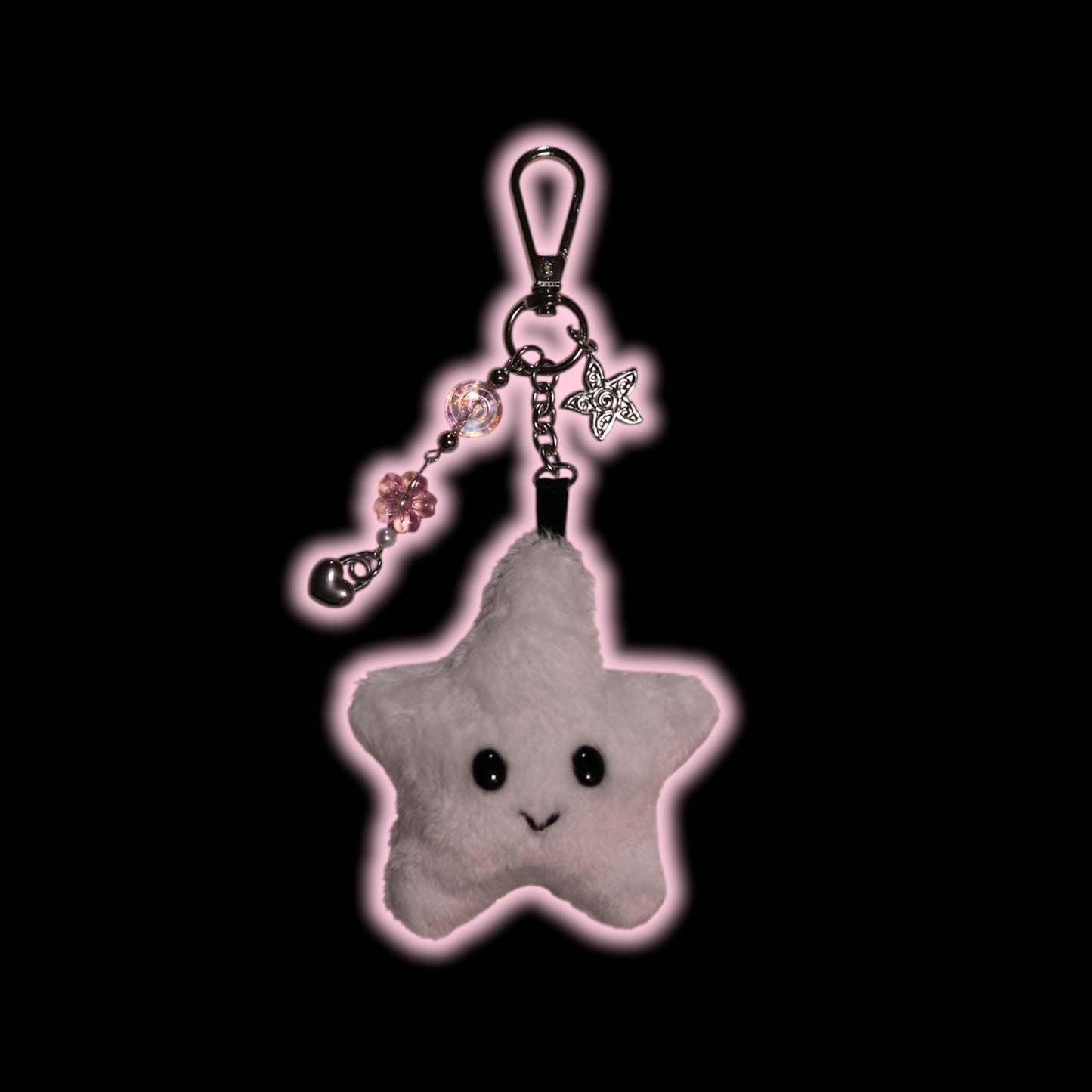 Star-shaped plush keychain with charms on a black background
