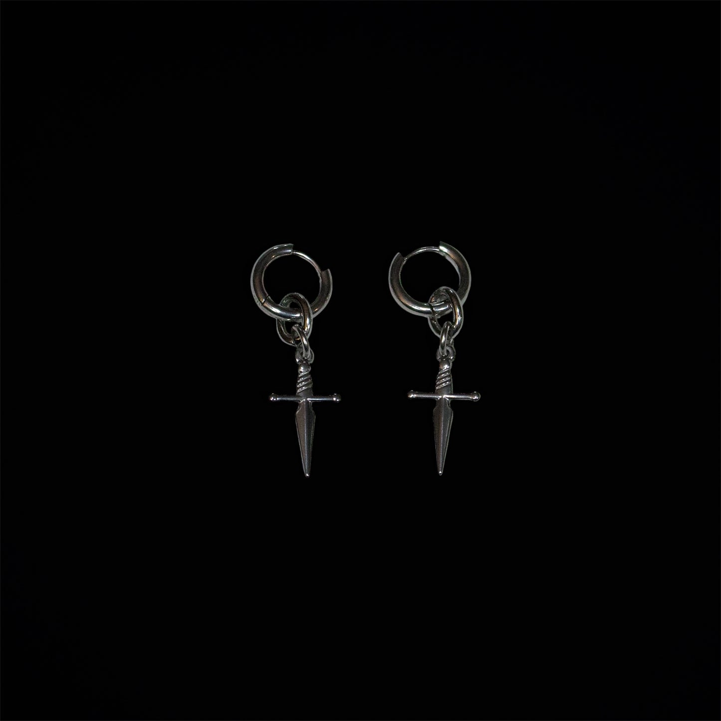 Pair of stainless steel dagger-shaped huggie earrings on a black background
