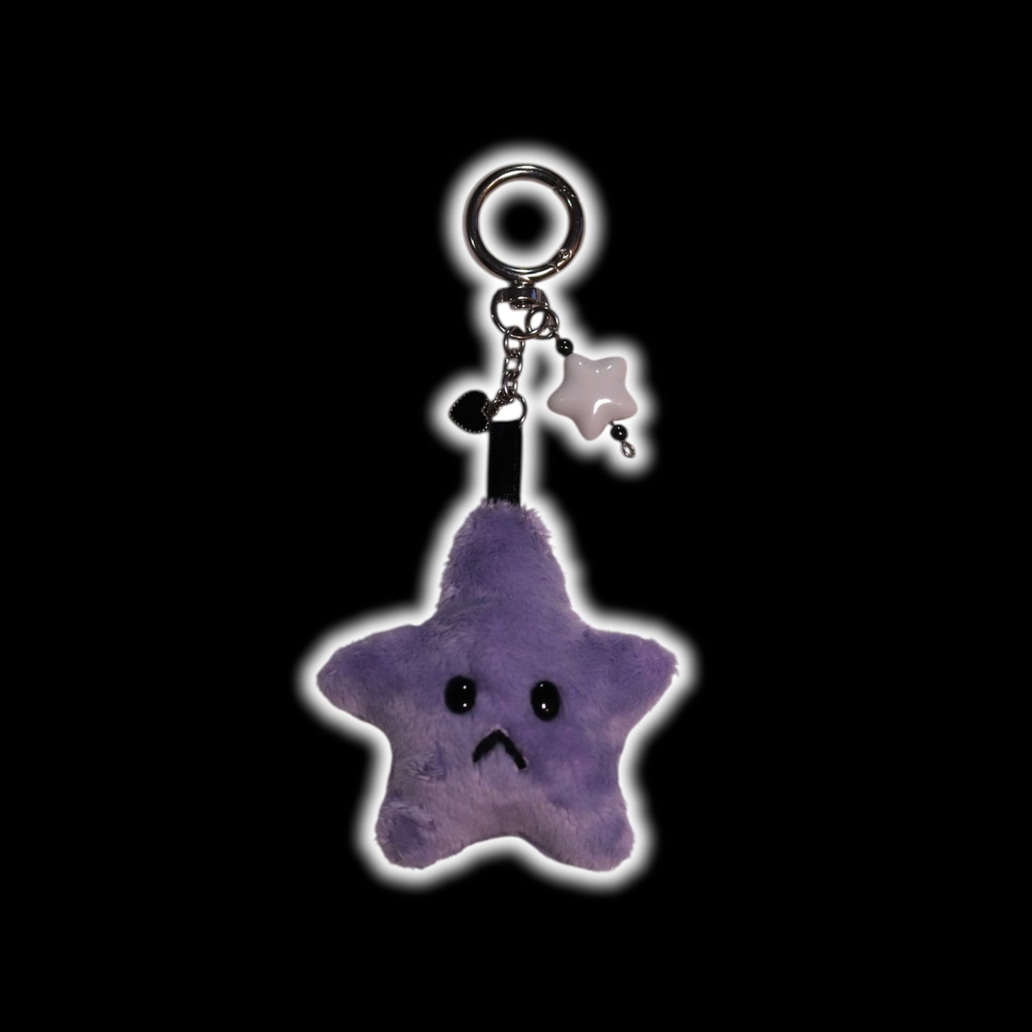 Purple star-shaped keychain with a sad face on a black background