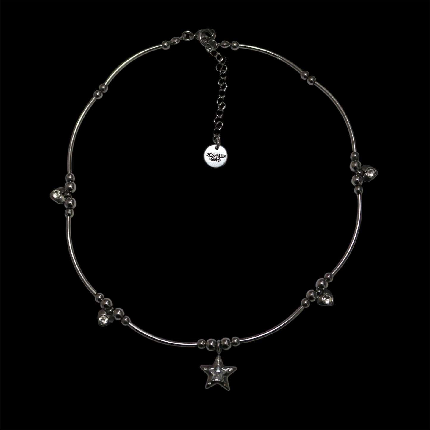 Stainless steel necklace with center star charm and additional heart charms on a black background