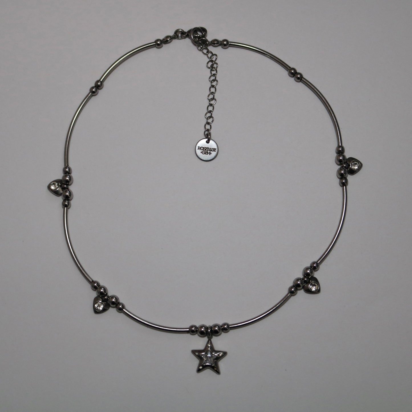 Silver necklace with star pendant and additional heart charms on a white background