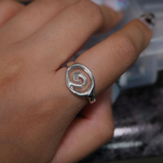 ROSEBLUEGEM- Silver spiral ring on a finger with a blurred background