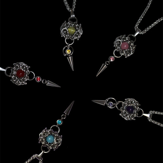 Five gothic-style pendants with gemstones on a black background