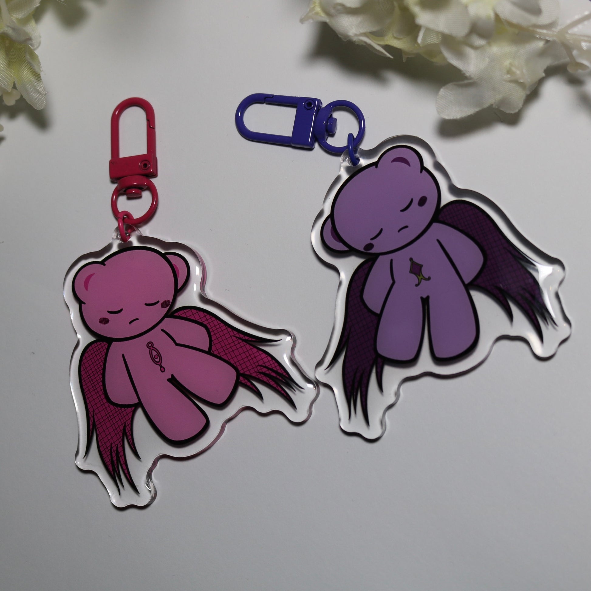 Two bear keychains (pink and purple) on a white background