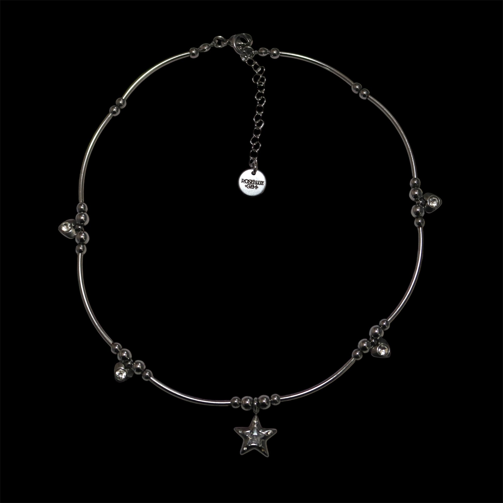 Stainless steel necklace with center star charm and additional heart charms on a black background
