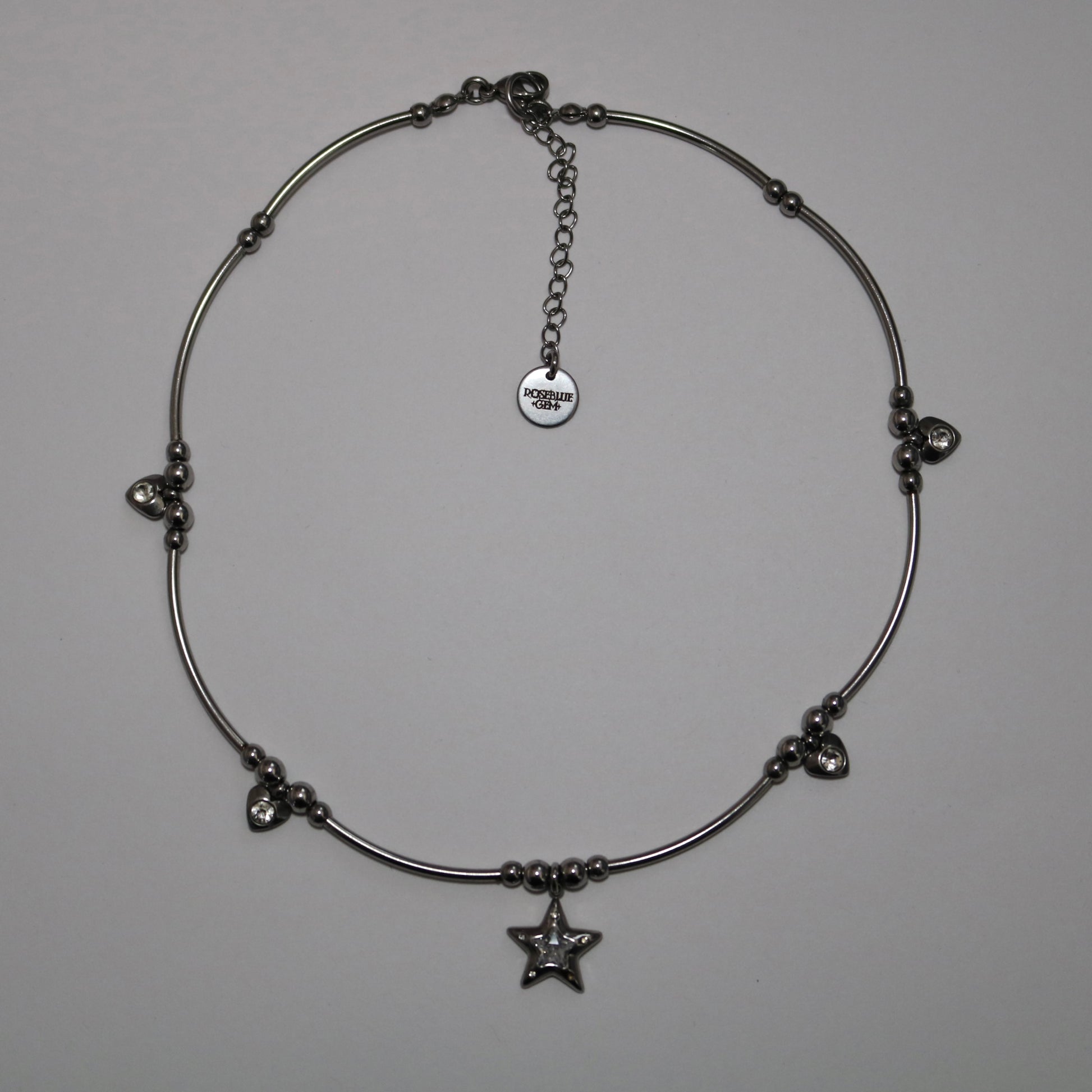 Silver necklace with star pendant and additional heart charms on a white background