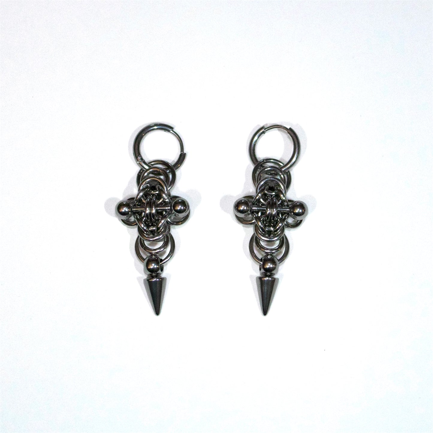 Pair of stainless steel earrings with cross chainmail byzantine design and adorned by a spike and a barbell piercing on a white background